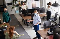 Office staff respecting social distancing during a meeting. Group of business men and women having a meeting in office during corona virus pandemic.