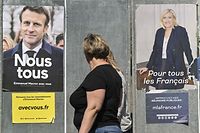 Pedestrians walk past campaign posters of French President and La Republique en Marche (LREM) party candidate for re-election Emmanuel Macron (L) and French far-right party Rassemblement National (RN) presidential candidate Marine Le Pen in Eguisheim, eastern France, on April 21, 2022, ahead of the second round of France's presidential election. - French voters head to the polls for a run-off vote between Macron and Le Pen on April 24, 2022. (Photo by SEBASTIEN BOZON / AFP)
