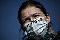 A health worker wearing a mask reading "on strike" takes part in a demonstration in Bordeaux, southwestern France on January 11, 2022, to protest against working conditions and the level of financial means for hospitals in France. (Photo by Philippe LOPEZ / AFP)