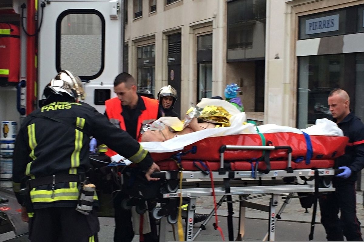 Firefighters carry an injured man on a stretcher in front of the offices of the French satirical newspaper Charlie Hebdo in Paris on January 7, 2015, after armed gunmen stormed the offices leaving at least one dead according to a police source and "six seriously injured" police officers according to City Hall. AFP PHOTO / PHILIPPE DUPEYRAT