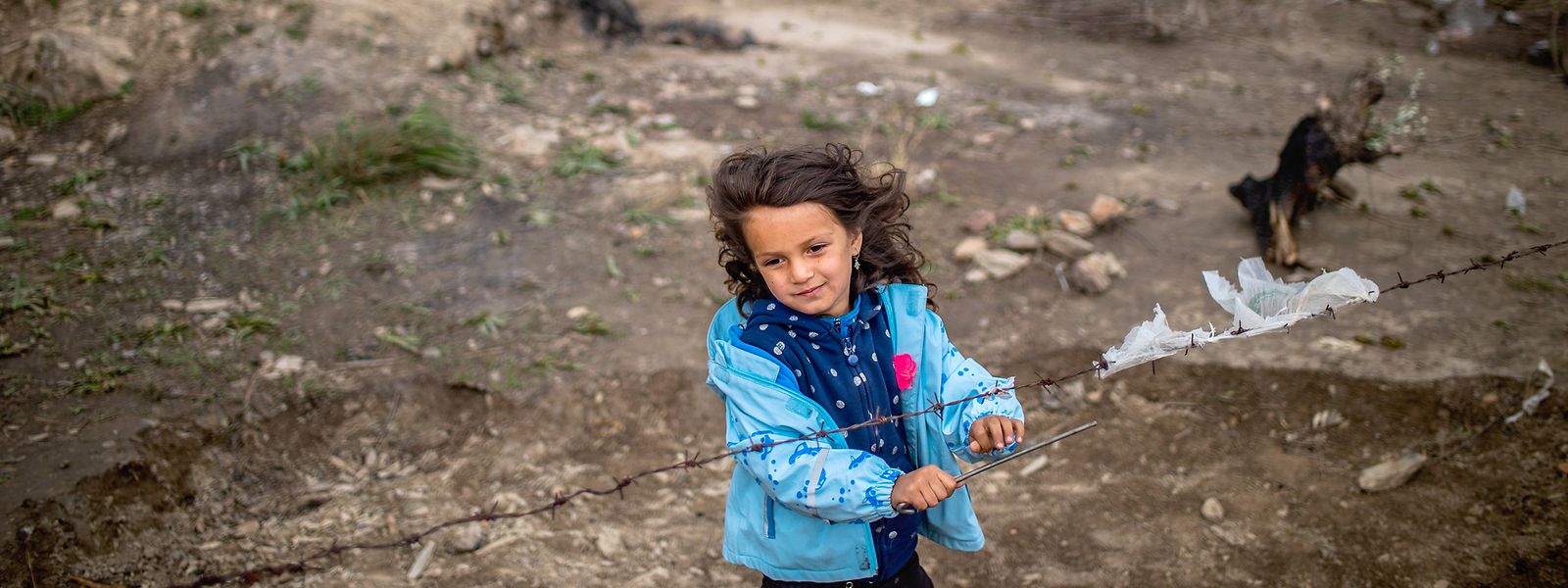 Ein kleines Mädchen steht am Stacheldrahtzaun in einem provisorischen Zeltlager in der Nähe des Camps für Migranten in Moria.
