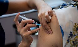A healthcare worker gives a dose of the Coronavac vaccine to a woman at a vaccination center in the Bicentenario Park, in Santiago, on February 10, 2021. - Chile surpassed one million people vaccinated against COVID-19 on February 9, 2021, six days after starting the mass immunization process in older adults, who joined the medical staff that has already been inoculated since December, the Ministry of Health reported. (Photo by Martin BERNETTI / AFP)
