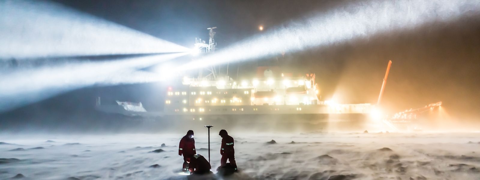 AWI-Meereisphysikers arbeiten bei auffrischendem Wind und zunehmender Schneedrift während einer Polarsternexpedition auf dem Meereis.