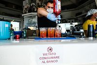 A placard reading " forbidden eat or drink at the counter " is seen as a barman prepares Spritz cocktails in a seafront coffee bar in Ostia, west of Rome, as the country eases lockdown measures taken to curb the spread of the COVID-19 pandemic, caused by the novel coronavirus. - Restaurants and churches reopened in Italy from May 18, 2020 as part of a fresh wave of lockdown easing in Europe and a gradual return to normality after two-month lockdown. (Photo by Andreas SOLARO / AFP)