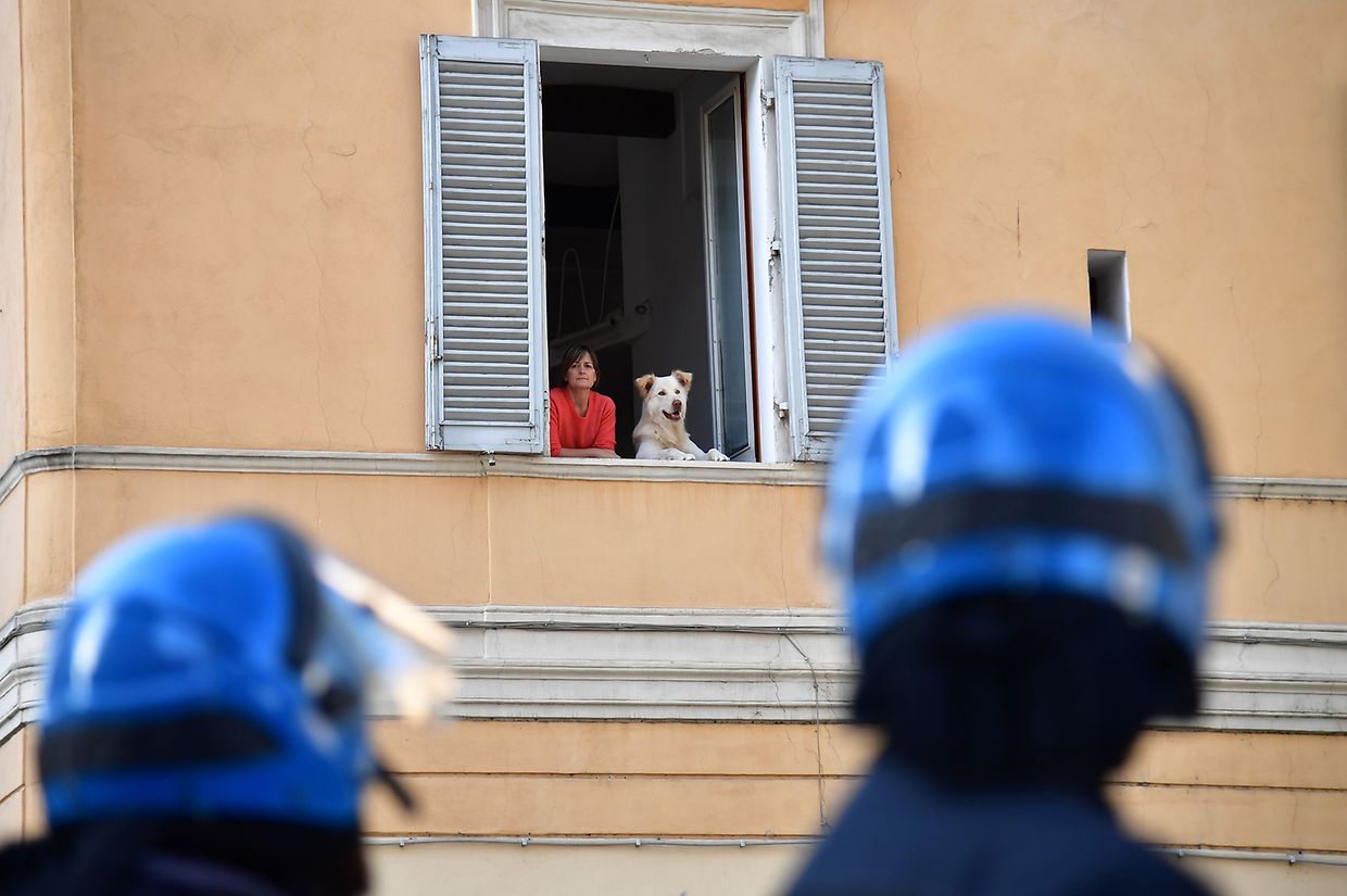 Eine Frau beobachtet mit ihrem Hund die Gegendemo in Rom. 