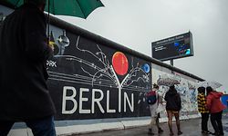 09.11.2019, Berlin: Touristen gehen am Werk «Berlyn» des Künstlers Gerhard Lahr an der East Side Gallery, der ehemaligen Berliner Mauer, vorbei. Foto: Gregor Fischer/dpa +++ dpa-Bildfunk +++