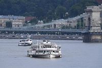 Sightseeing cruises are seen on the Danube river on May 30, 2019 in Budapest during the operations to pull out of the water the "Mermaid" sightseeing boat that sank overnight after colliding with a larger vessel in pouring rain. - Hungarian police launched a criminal investigation into one of the country's worst boat accidents that left at least seven South Korean tourists dead and 21 others missing. (Photo by Attila KISBENEDEK / AFP)