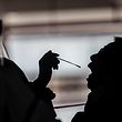 A taxi driver (R) gets tested by health workers (L) for coronavirus COVID-19 at a makeshift testing station in a carpark in Hong Kong on July 19, 2020. - The deadly coronavirus is spreading out of control in Hong Kong with a record 100 new cases confirmed, the finance hub's leader said as she tightened social distancing measures to tackle the sudden surge in infections. (Photo by ISAAC LAWRENCE / AFP)