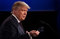 US President Donald Trump looks at his mask as he speaks with Democratic Presidential candidate and former US Vice President Joe Biden during the first presidential debate at Case Western Reserve University and Cleveland Clinic in Cleveland, Ohio, on September 29, 2020. - US President Donald Trump, 74, was forced off the campaign trail on October 2, 2020, after testing positive for Covid-19. Trump announced on Twitter that he and First Lady Melania Trump, 50, had tested positive and were going into quarantine. (Photo by JIM WATSON / AFP)