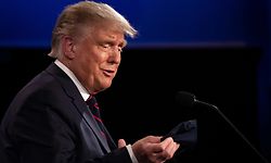 US President Donald Trump looks at his mask as he speaks with Democratic Presidential candidate and former US Vice President Joe Biden during the first presidential debate at Case Western Reserve University and Cleveland Clinic in Cleveland, Ohio, on September 29, 2020. - US President Donald Trump, 74, was forced off the campaign trail on October 2, 2020, after testing positive for Covid-19. Trump announced on Twitter that he and First Lady Melania Trump, 50, had tested positive and were going into quarantine. (Photo by JIM WATSON / AFP)