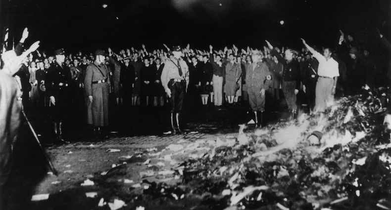 May 1933:  German soldiers and civilians give the Nazi salute as thousands of books smoulder during one of the mass book-burnings implemented throughout the country to destroy non-Aryan publications.  (Photo by Keystone/Getty Images)