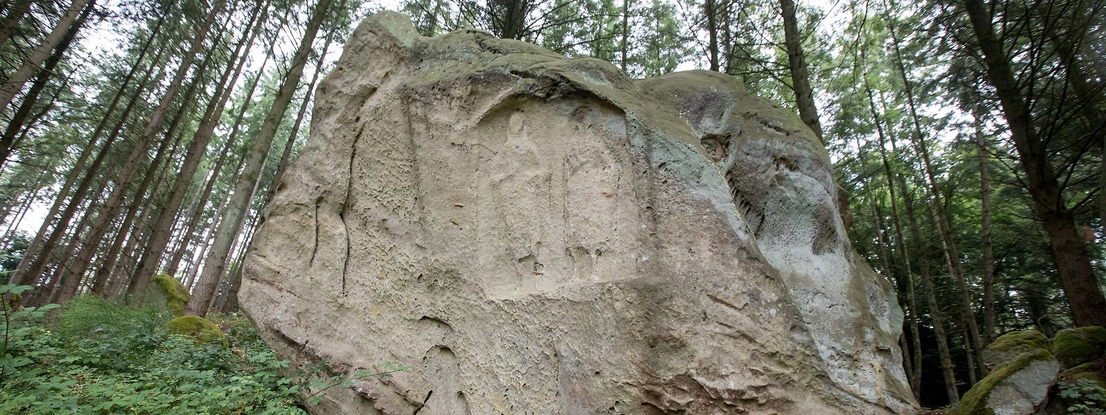 Der älteste Grabstein Luxemburgs liegt an einem gut frequentierten Wanderweg der Gemeinde  Junglinster. Die zwei Meter hohen Figuren sind weithin sichtbar. 