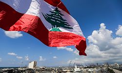 This picture taken on August 9, 2020 shows a Lebanese flag flying along a bridge near the port of Lebanon's capital Beirut, while in the background are seen the damaged grain silos opposite the blast site of a colossal explosion due to a huge pile of ammonium nitrate that had languished for years at a port warehouse. - The huge chemical explosion that hit Beirut's port, devastating large parts of the Lebanese capital and claiming over 150 lives, left a 43-metre (141 foot) deep crater, a security official said. The blast Tuesday, which was felt across the country and as far as the island of Cyprus, was recorded by the sensors of the American Institute of Geophysics (USGS) as having the power of a magnitude 3.3 earthquake. (Photo by JOSEPH EID / AFP)