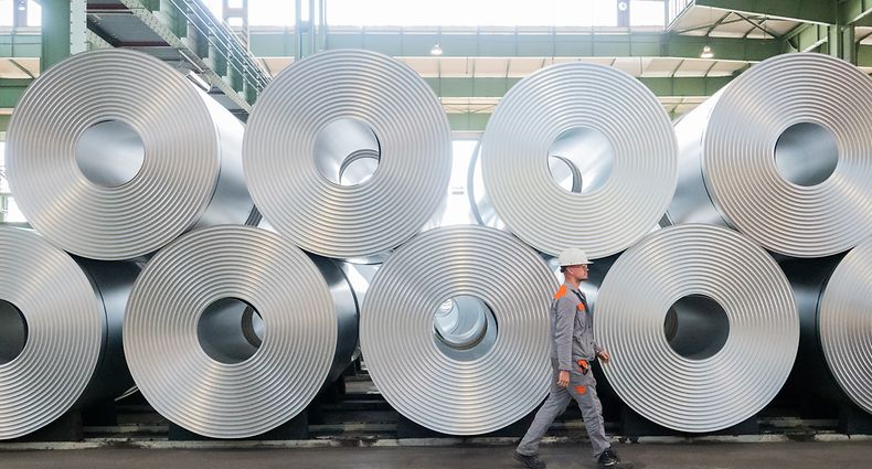 ARCHIV - 13.07.2020, Niedersachsen, Salzgitter: Ein Mitarbeiter geht bei der Salzgitter AG an aufgewickeltem Stahl (Coils) vorbei. Salzgitter AG gibt am 11.08.2021 die Halbjahreszahlen bekannt. Foto: Hilal Özcan/dpa +++ dpa-Bildfunk +++