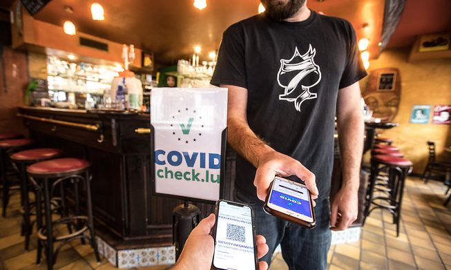 A waiter checks a customer's CovidCheck certificate