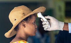 A shop assistant manning the entrance of a supermarket measures the temperature of shoppers on the first day of a 21 day lockdown on March 30, 2020 in Bulawayo, Zimbabwe. - Zimbabwean President Emmerson Mnangagwa declared a 21-day lockdown from March 30, 2020, curtailing movement within the country, shutting most shops and suspending flights in and out of Zimbabwe. (Photo by ZINYANGE AUNTONY / AFP)