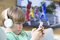 Child playing with a smartphone next to the television. (Photo by: BSIP/UIG via Getty Images)