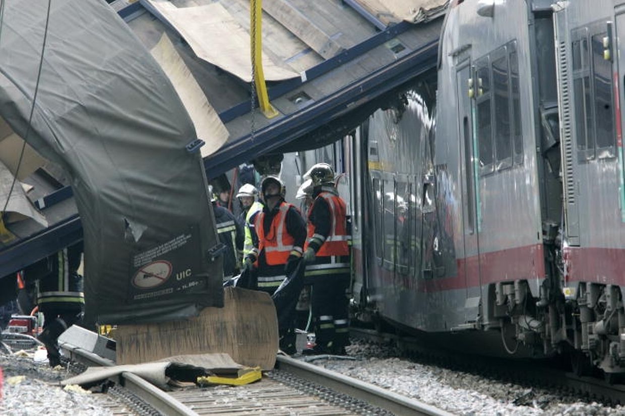 Un des wagons du train de marchandises arrête sa course en travers des voies: l'avant au sol et l'arrière sur le toit du wagon transportant les voyageurs. 