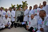 Doctors and nurses of Cuba's Henry Reeve International Medical Brigade pose with a portrait of Cuban late leader Fidel Castro as they are bid farewell before travelling to hard-hit Italy to help in the fight against the coronavirus COVID-19 pandemic, at the Central Unit of Medical Cooperation in Havana, on March 21, 2020. - Italy on Saturday shut all non-essential factories after recording another record coronavirus toll that brought its fatalities to 4,825 -- over a third of the world's total and a grim reminder that the pandemic remains out of control. (Photo by Yamil LAGE / AFP)