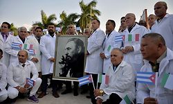 Doctors and nurses of Cuba's Henry Reeve International Medical Brigade pose with a portrait of Cuban late leader Fidel Castro as they are bid farewell before travelling to hard-hit Italy to help in the fight against the coronavirus COVID-19 pandemic, at the Central Unit of Medical Cooperation in Havana, on March 21, 2020. - Italy on Saturday shut all non-essential factories after recording another record coronavirus toll that brought its fatalities to 4,825 -- over a third of the world's total and a grim reminder that the pandemic remains out of control. (Photo by Yamil LAGE / AFP)