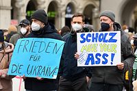 26.02.2022, Bayern, München: Demonstranten halten Plakate mit der Aufschrift "Frieden für die Ukraine" und "Scholz move your ass!" bei einer Demonstration auf dem Odeonsplatz gegen Russlands Angriff auf die Ukraine. Foto: Tobias Hase/dpa +++ dpa-Bildfunk +++