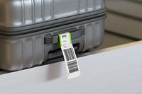 Gray suitcase on airport conveyor belt with abstract NY flight number label