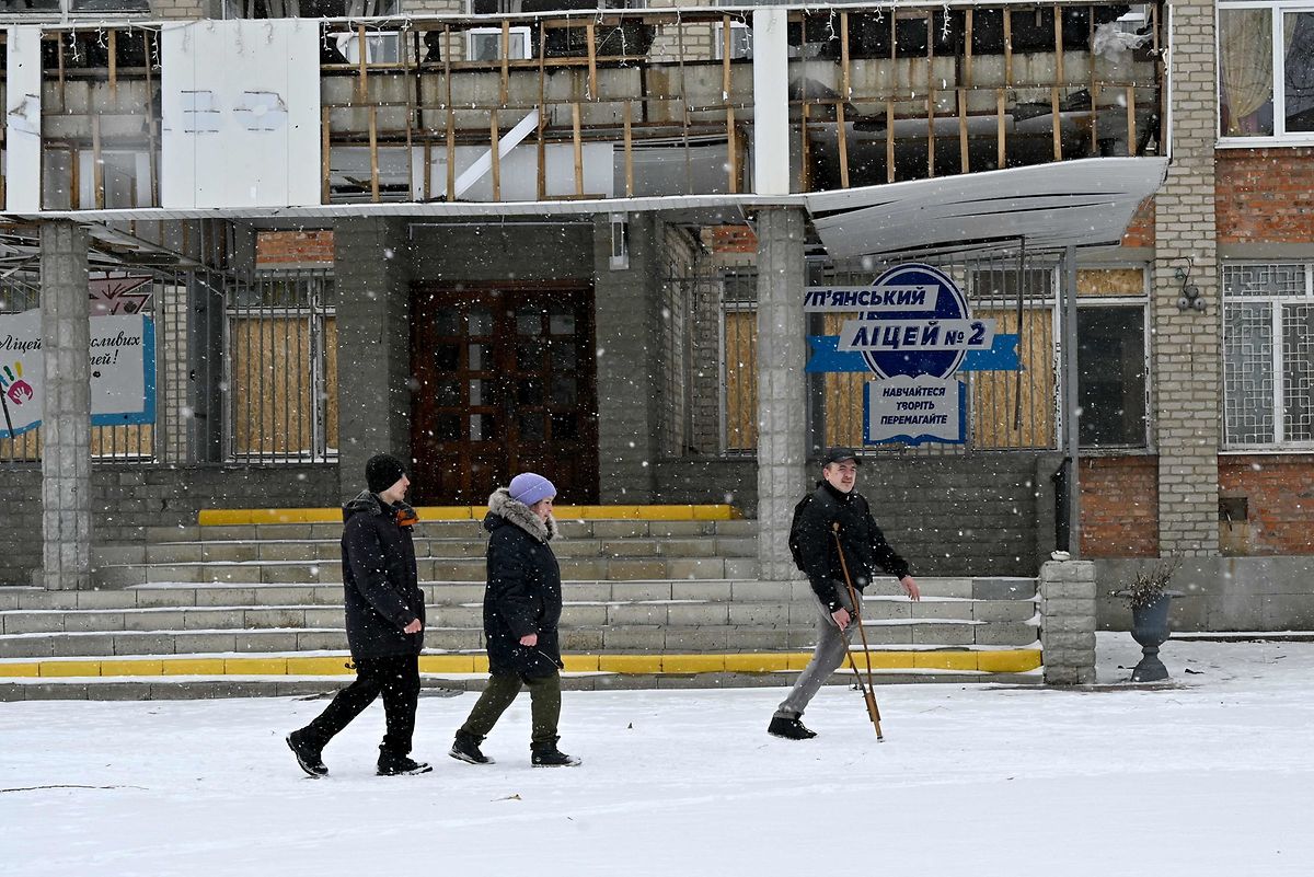 Local residents walk past a high-school, partially destroyed as a result of Russian shelling of Kupyansk, Kharkiv region, on February 13, 2023