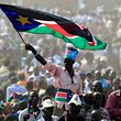 A man waves South Sudan's national flag as he attends the Independence Day celebrations in the capital Juba in this July 9, 2011 file photo. Fighting spreading along Sudan's new southern border could develop into a coordinated insurgency and encourage efforts to mount a political challenge to President Omar Hassan al-Bashir. To match Analysis SUDAN-FIGHTING/ REUTERS/Thomas Mukoya/Files (SOUTH SUDAN - Tags: CIVIL UNREST POLITICS)