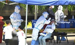 TOPSHOT - A health worker (2nd-L) wearing a protective suit takes a swab test on a woman in Beijing on June 16, 2020. - China reported another 27 domestically transmitted coronavirus cases in Beijing, where a fresh cluster linked to a wholesale food market has sparked WHO concern and prompted a huge trace-and-test programme. (Photo by Noel Celis / AFP)