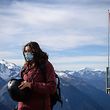 A skier wearing a protectivef as mask, against the spread of the Covid-19 (novel coronavirus), prepares to put on her helmet next to a Swiss flag above the ski resort of Verbier in the Swiss Alps on November 15, 2020. - The coronavirus crisis shuttered Switzerland's ski resorts in the spring, but they are banking on tighter precautions and the Swiss love of the mountains to save them as the winter season begins. (Photo by Fabrice COFFRINI / AFP)
