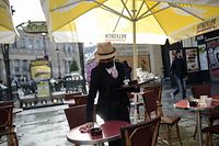 A memmer of staff clears a table at a cafe in Paris on May 19, 2021, as cafes, resteraunts and other businesses re-opened after closures during the coronavirus (Covid-19) pandemic. - Parisians have returned to their beloved cafe terraces and museums after a six-month Covid-forced hiatus, a glimmer of normal life resuming but India grappled with a record daily number of coronavirus deaths. (Photo by Lucas BARIOULET / AFP)