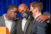 12.03.2021, USA, Minneapolis: Brandon Williams (l-r), Neffe von George Floyd, Philonise Floyd, jüngerer Bruder von George Floyd, und Jacob Frey, Bürgermeister von Minneapolis, stehen bei einer Pressekonferenz auf der Bühne neben Vertretern der Stadtverwaltung, Angehörigen von George Floyd und Anwälten. Fast ein Jahr nach dem Tod des Afroamerikaners George Floyd bei einem Polizeieinsatz in Minneapolis hat sich die Stadt mit der Familie auf einen Vergleich geeinigt. Dieser sieht die Zahlung von 27 Millionen US-Dollar (etwa 22,6 Millionen Euro) als Entschädigung vor. Der Stadtrat der Großstadt im Bundesstaat Minnesota habe die Vereinbarung am Freitag einstimmig gebilligt. Foto: Chris Juhn/ZUMA Wire/dpa +++ dpa-Bildfunk +++
