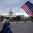 WASHINGTON, DC - JANUARY 08: A protester walks by as the American flag flies at half-staff at the U.S. Capitol on January 08, 2021 in Washington, DC. House Speaker Nancy Pelosi ordered the building's flags be flown at half-staff in honor of Capitol Police Officer Brian Sicknick, 42, who died after being injured during clashes with a pro-Trump mob at the Capitol on Jan. 6. Sicknick, a military veteran, was a 12-year member of the force.   John Moore/Getty Images/AFP
== FOR NEWSPAPERS, INTERNET, TELCOS & TELEVISION USE ONLY ==