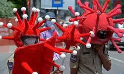 Polícias indianos com capacetes ilustrativos do SARS-CoV-2 para sensibilizar a população para a adoção das medidas sanitárias.