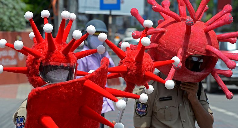 Polícias indianos com capacetes ilustrativos do SARS-CoV-2 para sensibilizar a população para a adoção das medidas sanitárias.