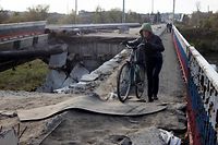 TOPSHOT - A local resident pushes his bike on destroyed bridge near Borivske, Kharkiv region on October 23, 2022. (Photo by Yevhen TITOV / AFP)