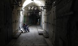 Two men sit in front of closed shops along a deserted alley in the Old City of Jerusalem on March 26, 2020, during the ongoing novel coronavirus pandemic crisis. (Photo by Ahmad GHARABLI / AFP)