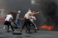 TOPSHOT - Palestinian protesters hurl rocks amid confrontations with Israeli security forces at the Hawara checkpoint south of Nablus city, in the occupied West Bank, on May 21, 2021, following demonstrations in support of Palestinians in Jerusalem's Sheikh Jarrah and the Gaza Strip. (Photo by JAAFAR ASHTIYEH / AFP)