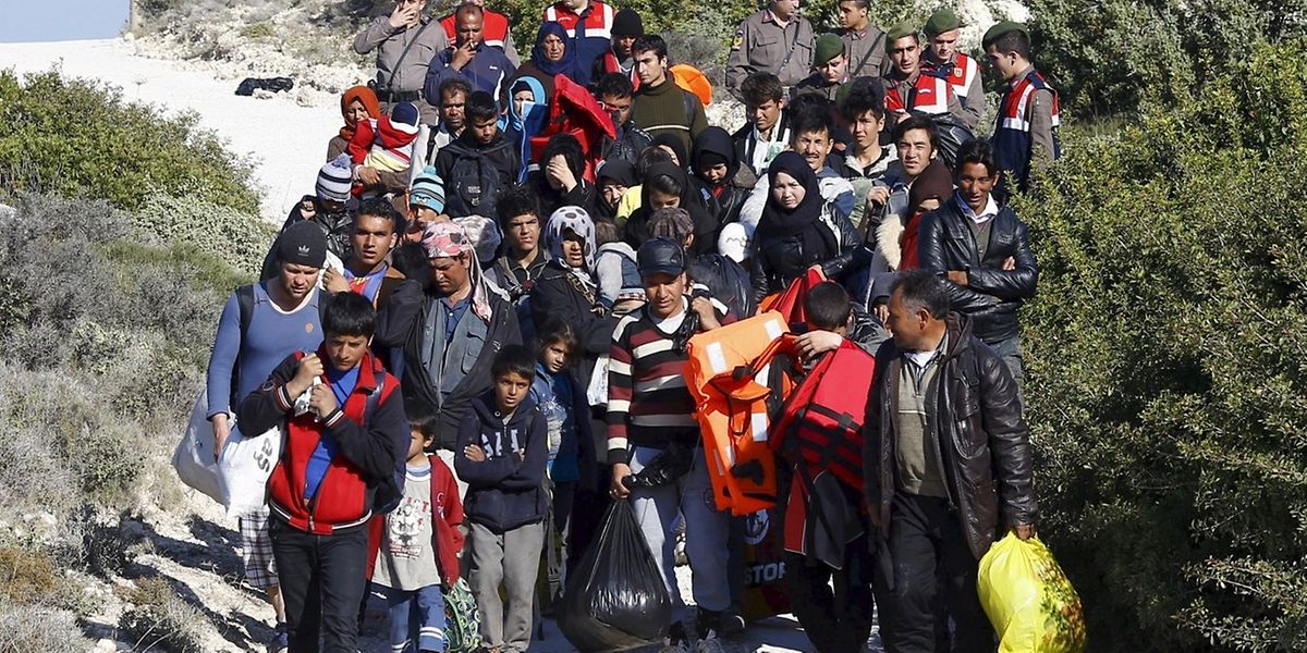 Türkische Polizeibeamte (im Hintergrund) begleiten eine Gruppe von Flüchtlingen zu Bussen, um sie an der Überfahrt nach Griechenland zu hindern.