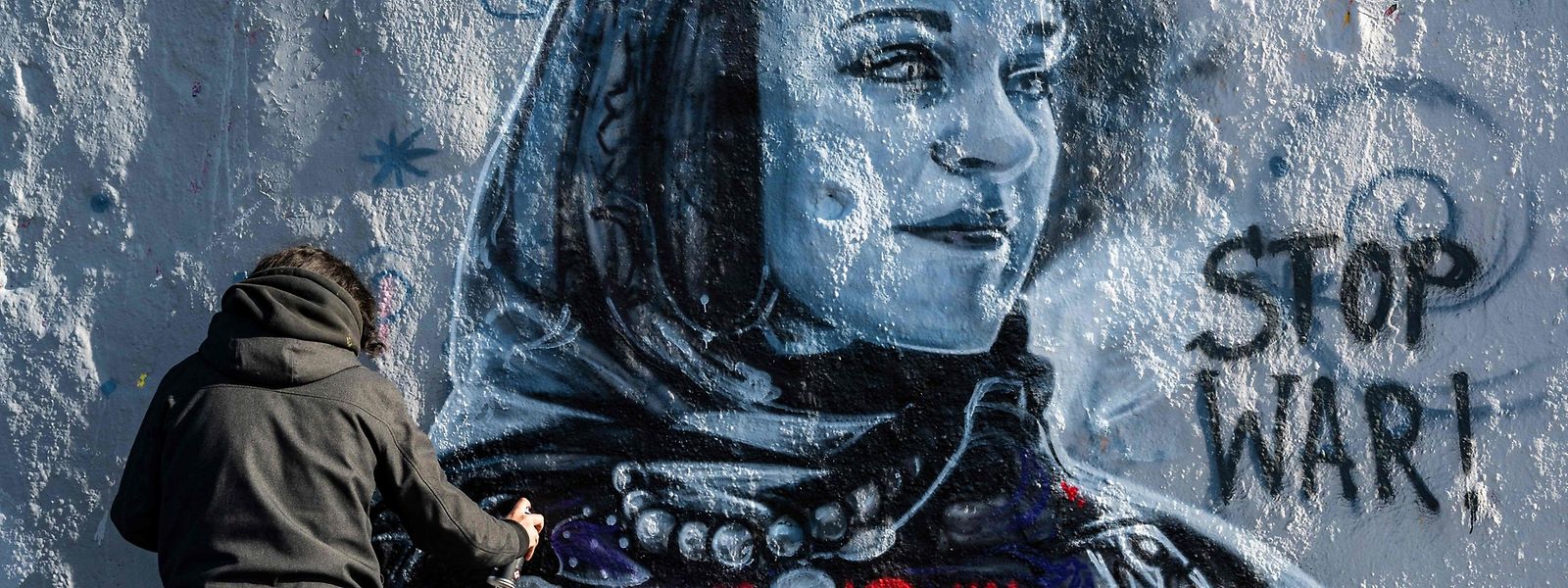 Der in Berlin lebende kolumbianische Straßenkünstler Arte Vilu arbeitet an einem Wandgemälde, das eine ukrainische Frau in traditioneller Kleidung zeigt.