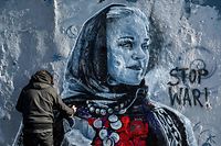 Berlin-based Colombian street artist Arte Vilu works on a mural featuring a Ukrainian woman in traditional dress, in Berlin on February 28, 2022. (Photo by John MACDOUGALL / AFP)