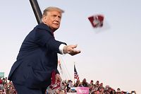 TOPSHOT - US President Donald Trump throws masks to supporters as he arrives to hold a Make America Great Again rally as he campaigns at Orlando Sanford International Airport in Sanford, Florida, October 12, 2020. (Photo by SAUL LOEB / AFP)