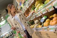 Happy Asian woman shopping at a food market and buying fresh organic fruits