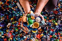 A worker poses with bottle caps collected in exchange for city bus tickets in Surabaya on March 3, 2022, before being resold to plastic recycling factories. (Photo by JUNI KRISWANTO / AFP)