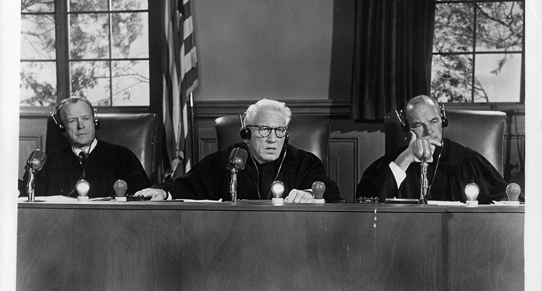Kenneth MacKenna, Spencer Tracy, and Ray Teal listening to testimony in a scene from the film 'Judgement At Nuremberg', 1961. (Photo by United Artists/Getty Images)