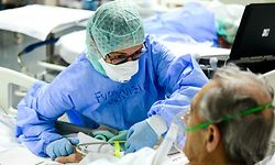 TOPSHOT - A member of the medical staff comforts a patient infected by the novel coronavirus at the COVID-19 division at the ASST Papa Giovanni XXIII hospital in Bergamo, on April 3, 2020. - Italy's three-week lockdown to stop the spread of COVID-19 has been extended through at least mid-April and its economy is expected to suffer its biggest peacetime shock since World War II. (Photo by Piero CRUCIATTI / AFP)
