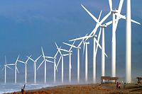 Villagers are dwarfed by giant windmills built by the Danish Development Agency, DANIDA, along the shores of Bangui, Ilocos Norte province in northern Philippines Wednesday Nov. 8, 2006. The sixteen giant "Bangui Windmills" built last year, are capable of generating 54 Megawatts of electricity and are the first such alternative source of energy in Southeast Asia. (AP Photo)