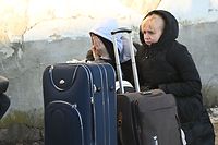 Ukrainian refugees sit at the side of the road as they arrived at the temporary refugee centre in a local primary school at Tiszabecs, eastern Hungary on February 28, 2022. - With bowls of goulash, offers of free lodging and rides to Budapest, or just a hug and kind word, Hungarians have rushed to the Ukrainian border to help refugees fleeing the Russian invasion. (Photo by Attila KISBENEDEK / AFP) / ALTERNATIVE CROP