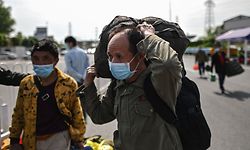 A man wearing a face mask walks along a road after passing through a checkpoint in Wuhan, in China's central Hubei province on April 6, 2020. - Wuhan, the central Chinese city where the coronavirus first emerged last year, partly reopened on March 28 after more than two months of near total isolation for its population of 11 million. (Photo by Hector RETAMAL / AFP)