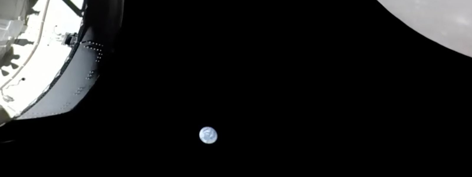 Eine Kamera an Bord der „Orion“-Kapsel zeigt das Raumschiff (l) im Weltraum, den Mond (r) und klein im Hintergrund die Erde.